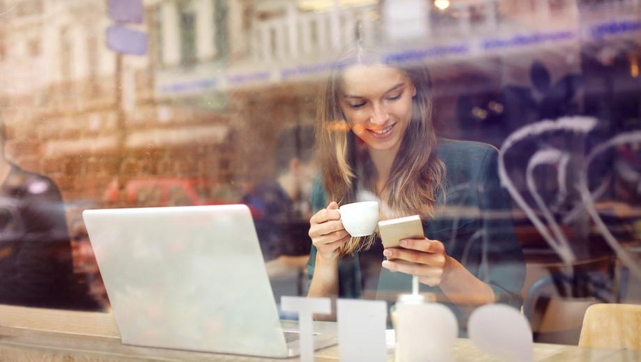 Frau mit Handy und Laptop im Cafe