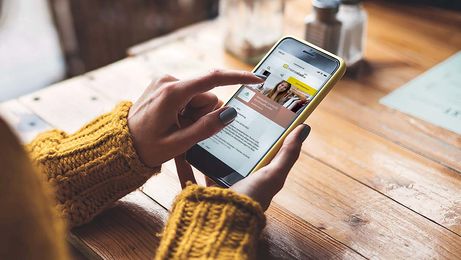 Frau in gelbem Pullover am Handy