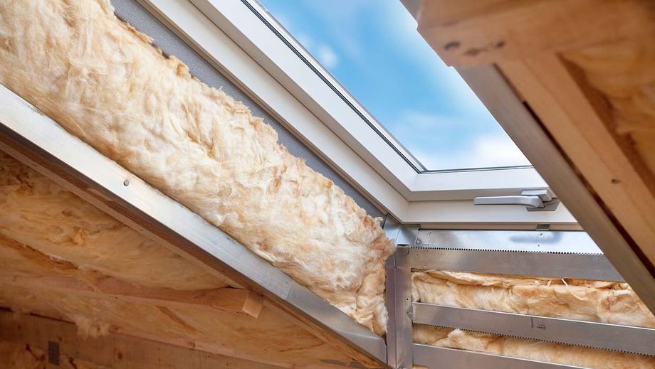 Ein Fenster in einer Dachschräge ohne Verkleidung, das Dämmmaterial in der Wand ist sichtbar