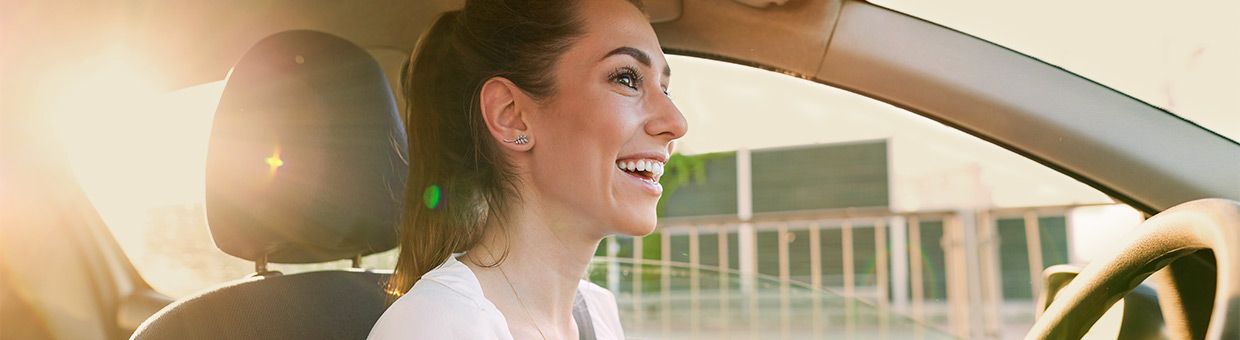 Auto-Abo: junge Frau zufrieden am Steuer eines abonnierten Autos