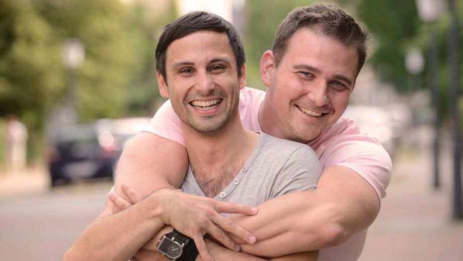 Ein homosexuelles Paar umarmt sich freudestrahlend.