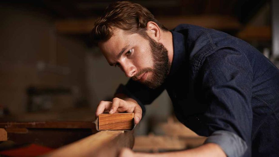 Ein Handwerker in Ausbildung bearbeitet Holz