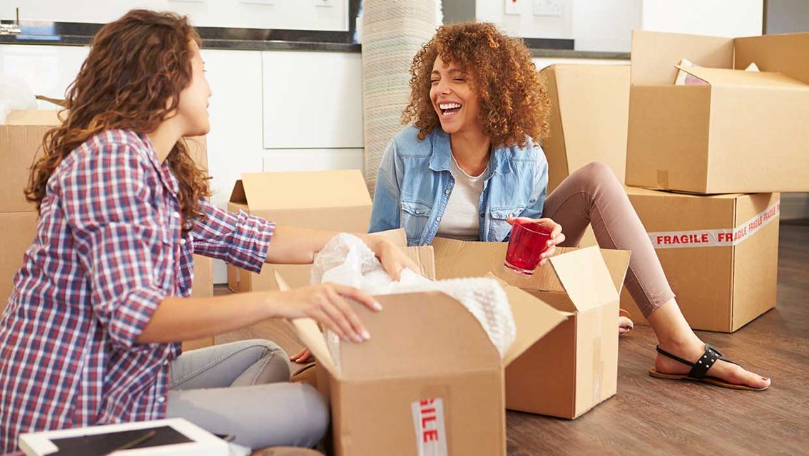 Zwei Frauen sitzen zwischen Umzugskartons
